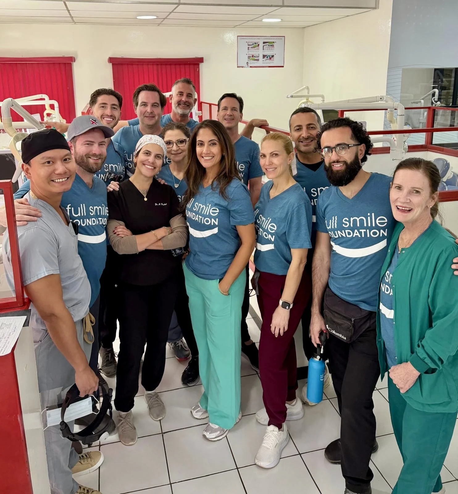 Group of dental professionals smiling in a dental clinic, some wearing matching blue t-shirts with the 'Full Smile Foundation' logo.