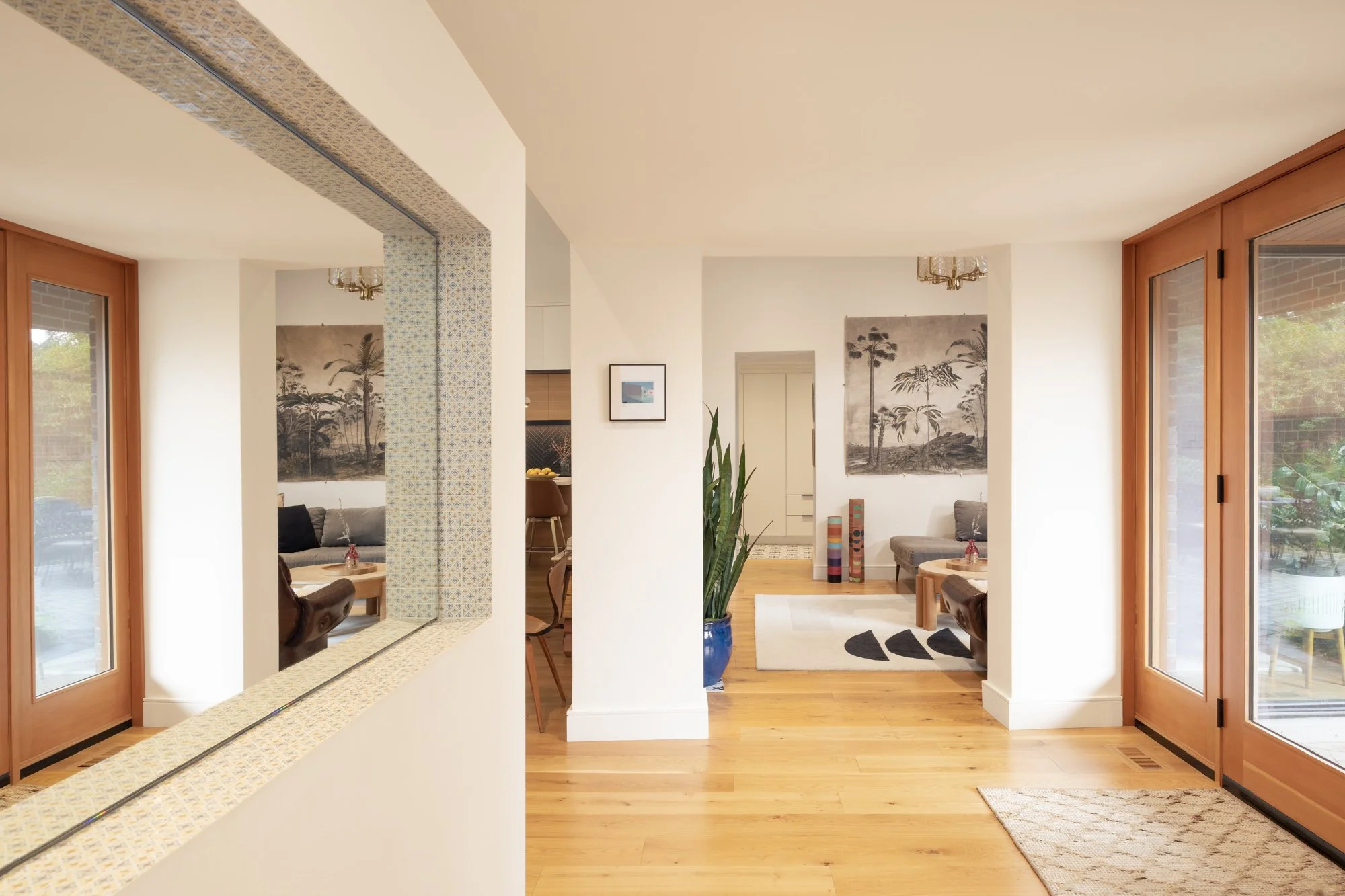 Living room with hardwood floors, large windows, and artwork of trees on the walls