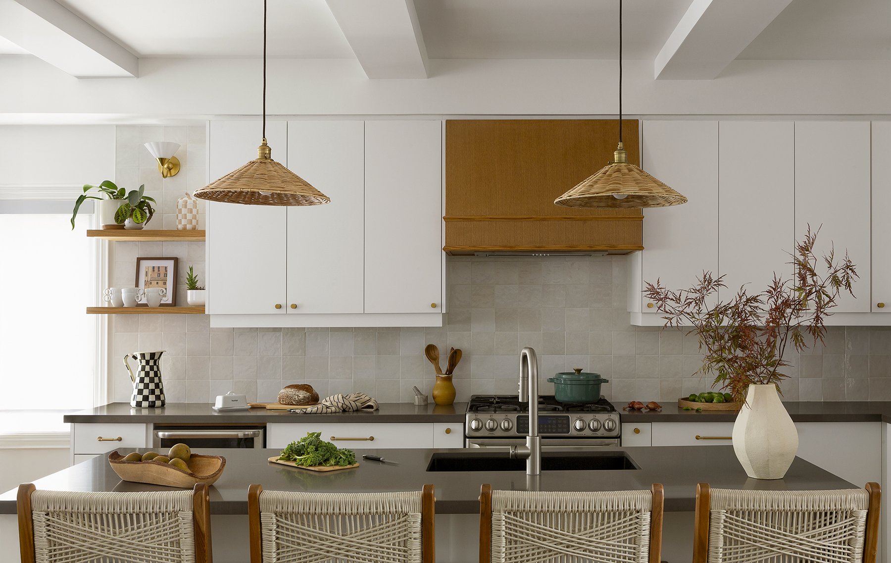 Modern kitchen with white cabinets, a gray countertop, and wood accents. Includes pendant lights, plants, dishes, and cooking utensils.