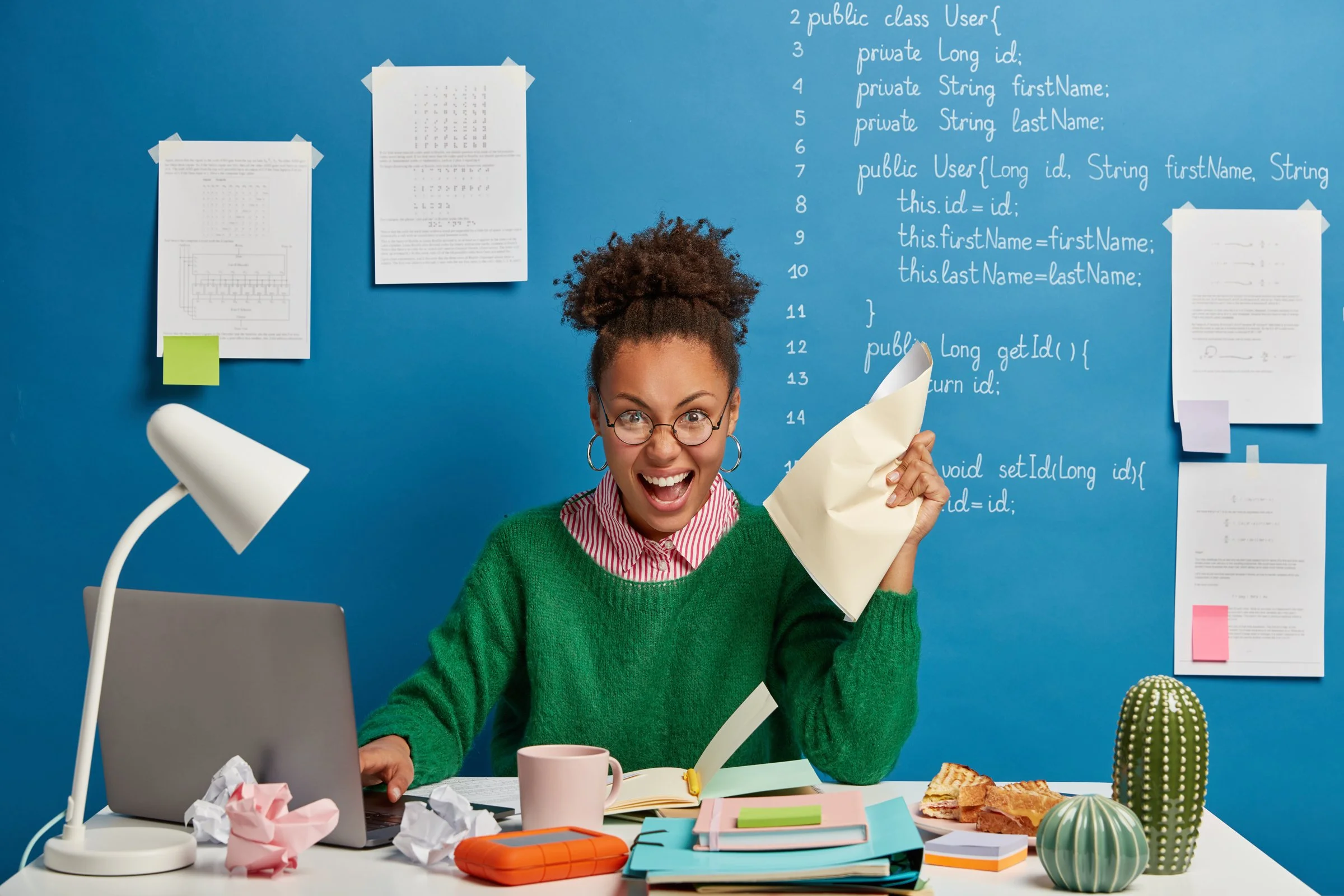 Very excited woman with notebooks and a crumpled piece of paper in her hand