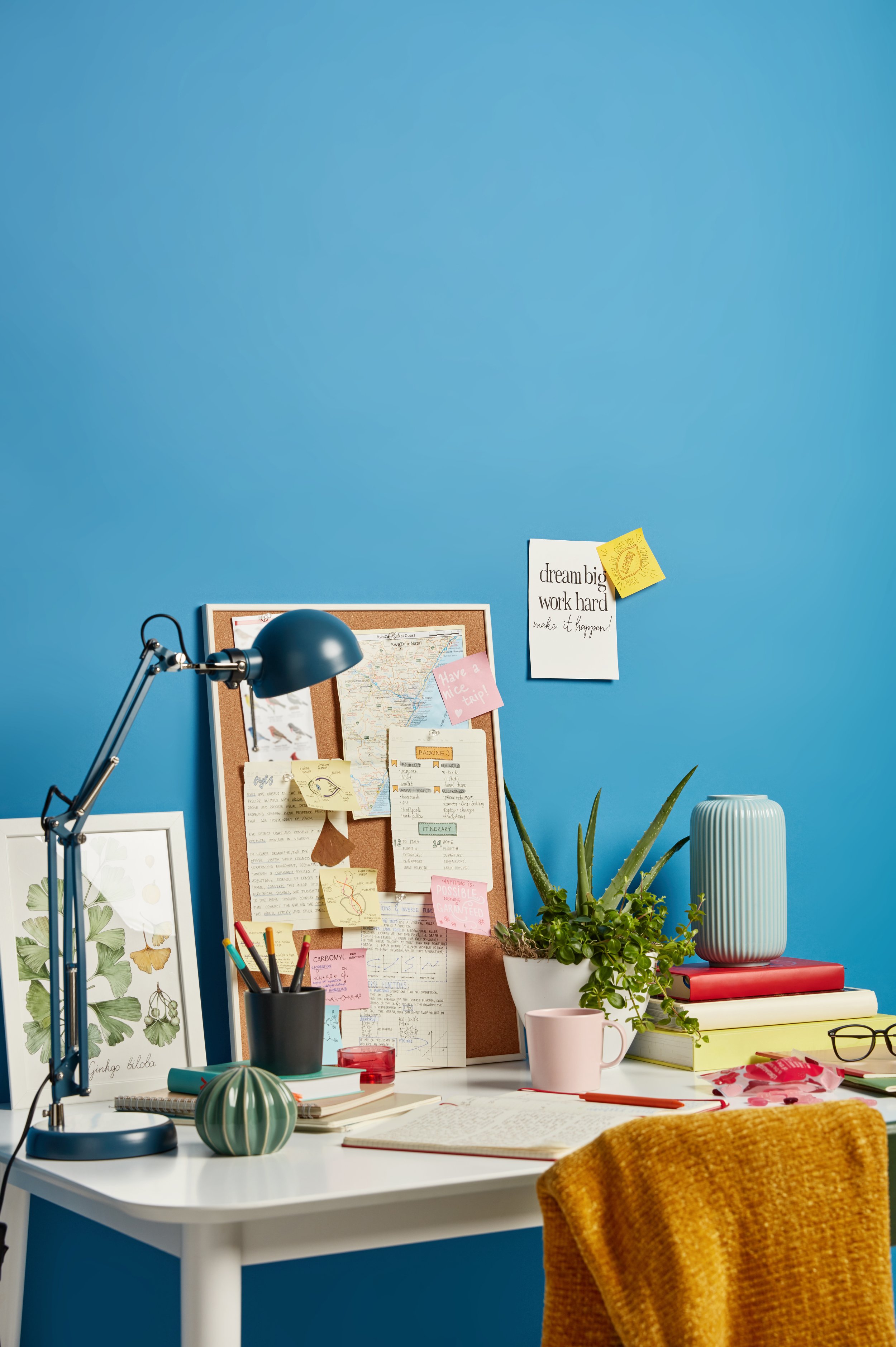 Workspace with blue wall and cork-board with lots of notes