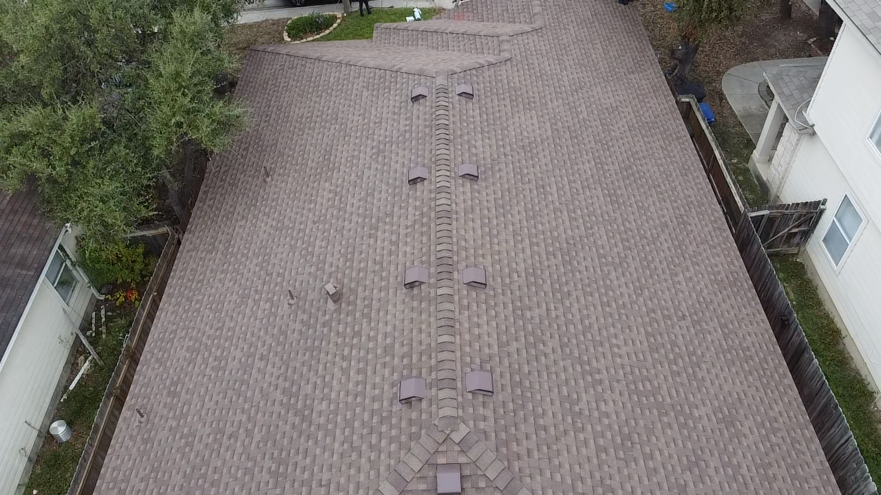 Aerial view of a house roof with brown shingles and multiple vents.