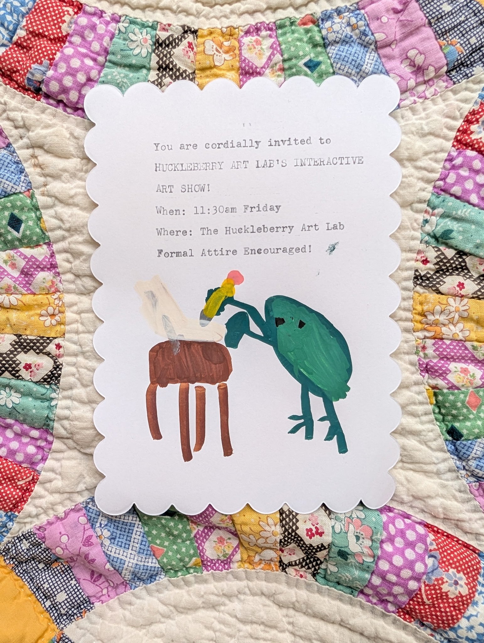Invitation card for Hucklberry Art Lab's interactive art show with colorful quilt border, featuring hand-painted illustrations of a chair and a plant.