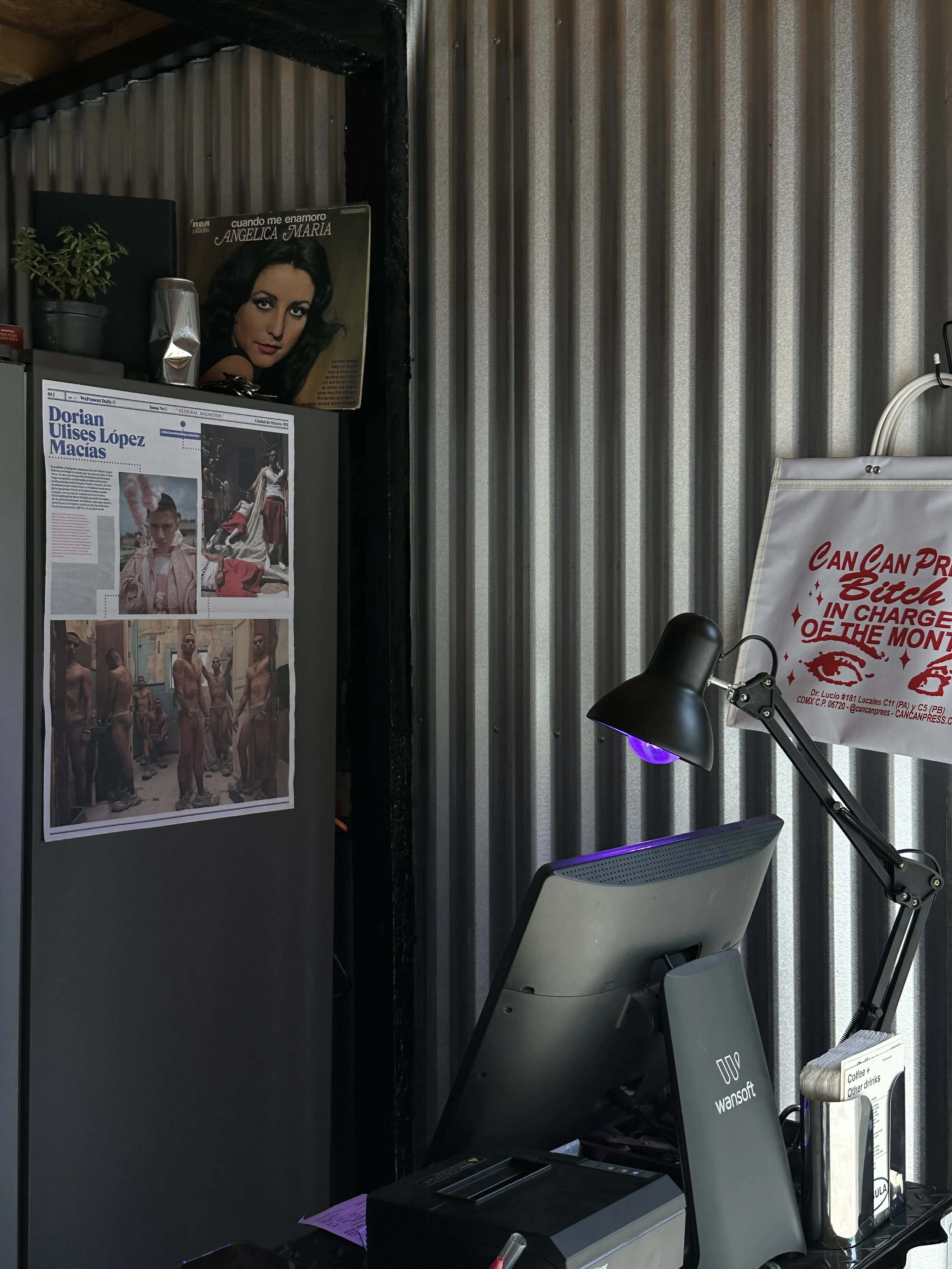 Elementos decorativos de Cápsula - Café de especialidad en La Punta con el punto de venta, la lámpara morada y portadas de periódico y vinyl