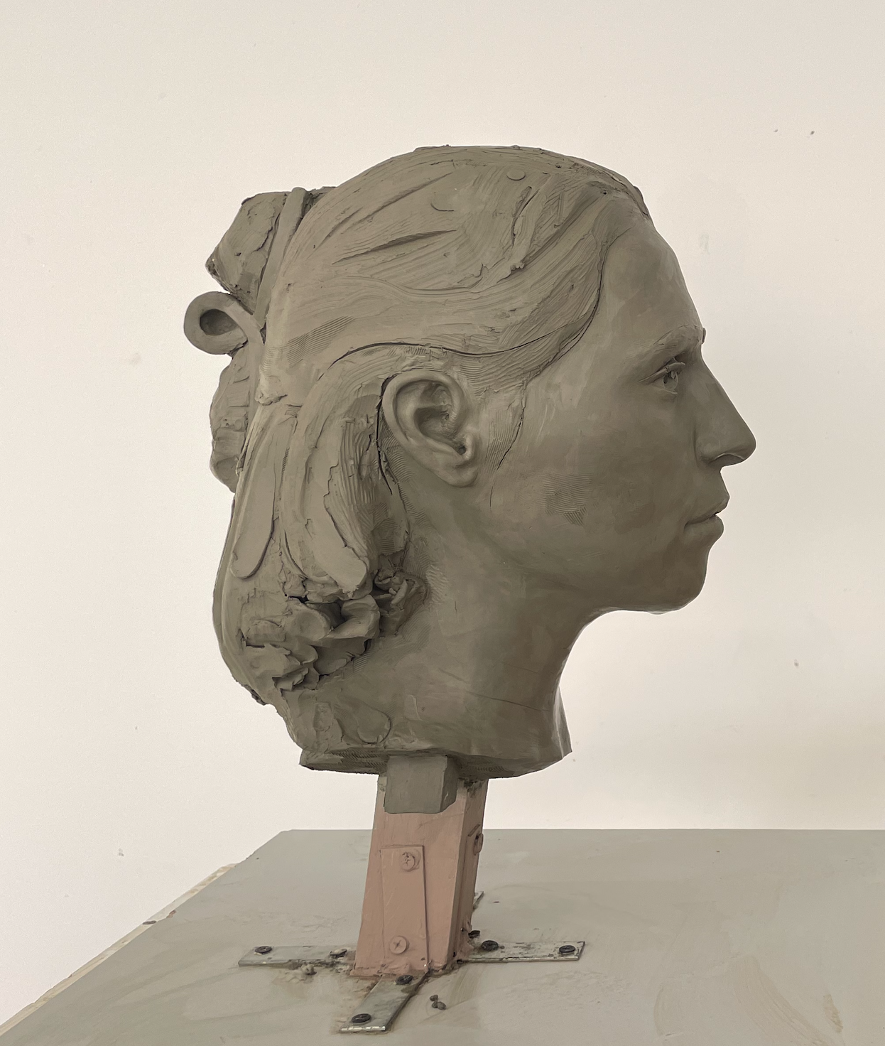 A sculpture of a woman's head, detailed with realistic features and textured hair, mounted on a stand.