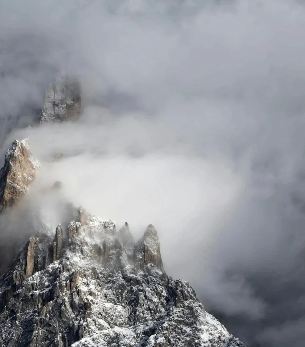 Snow-covered mountain peaks shrouded in thick fog and clouds.