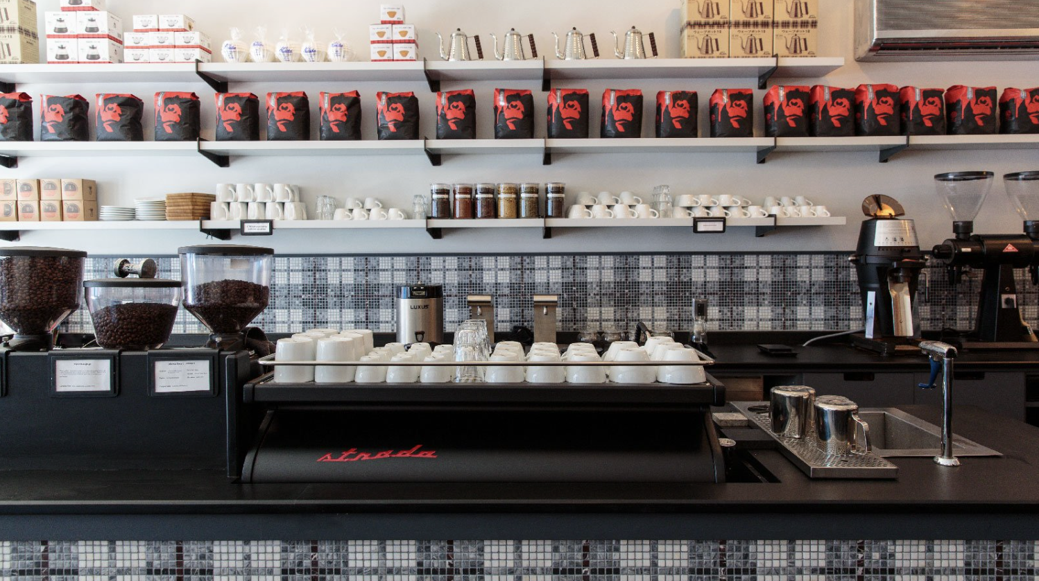 Coffee shop interior with shelves of coffee bags, cups, and coffee machines