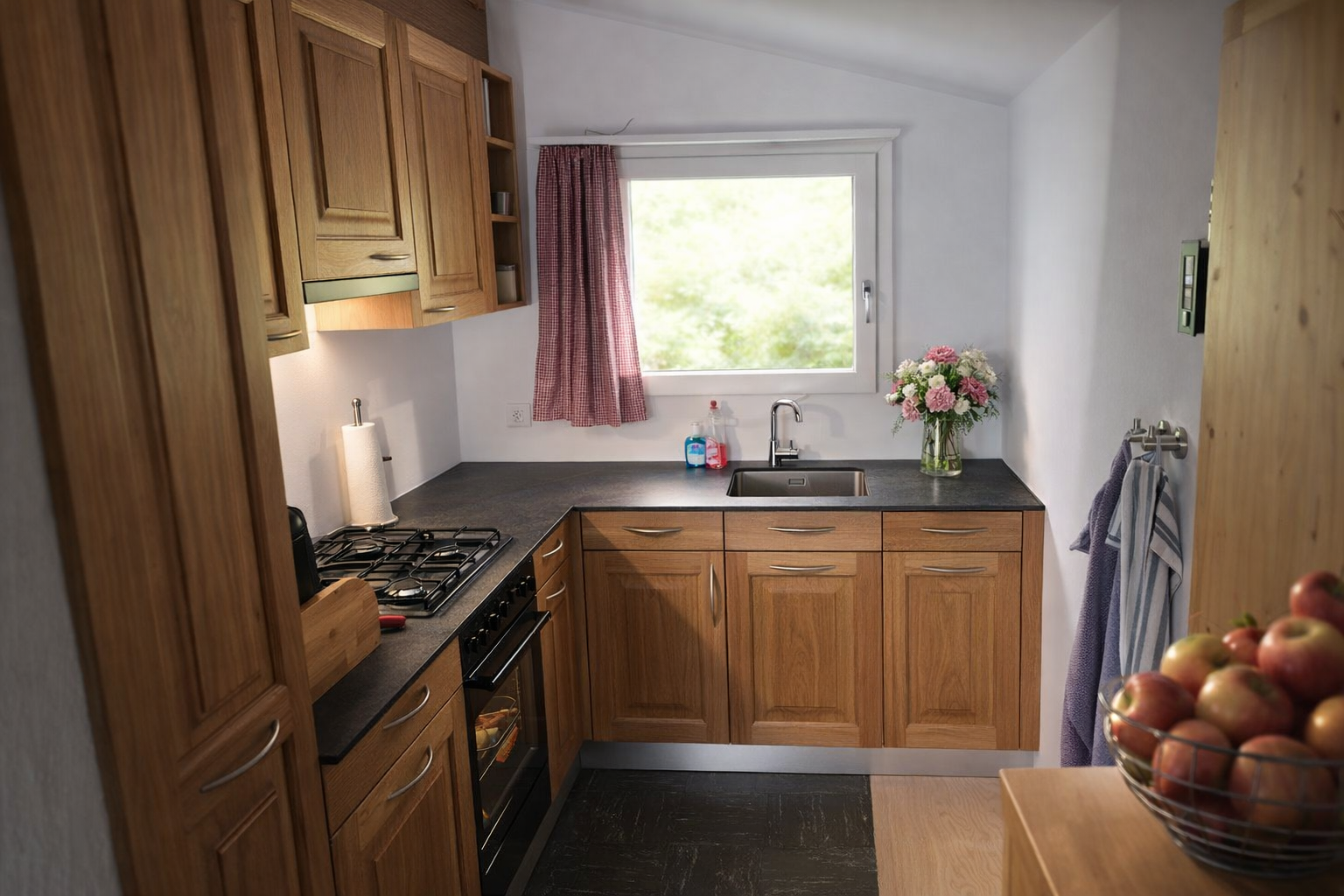 Kleine, helle Küche mit Holzschränken, Herd, Spüle, Fenster, rosa Blumen und Obstkorb