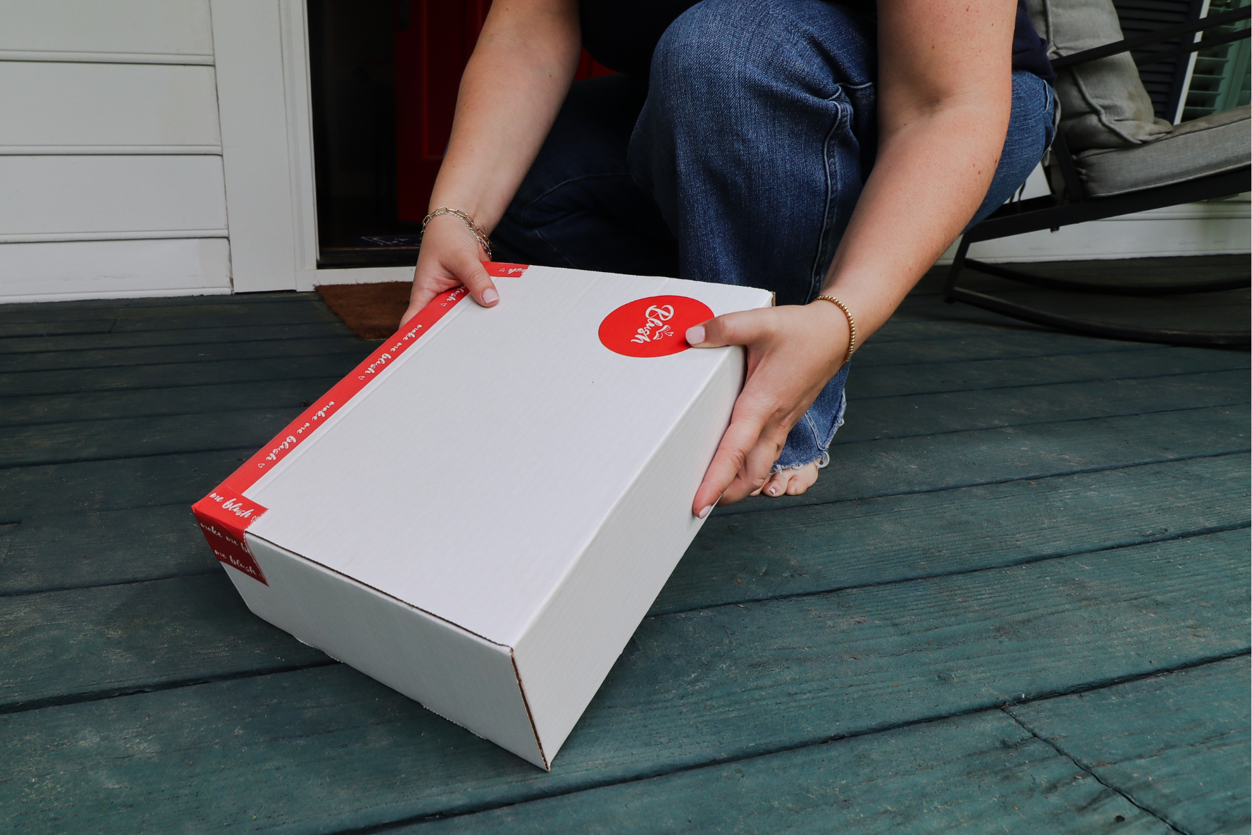 person placing a blush book bundle on the porch