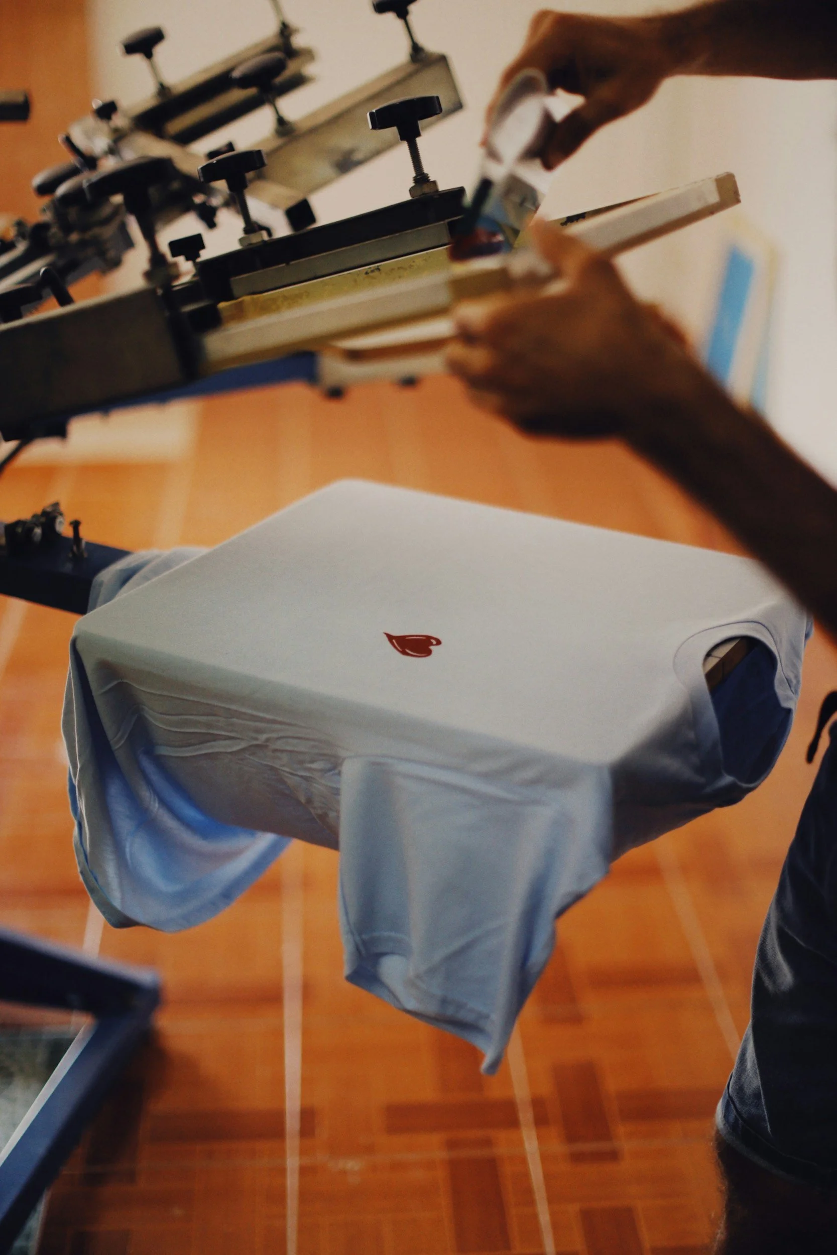 Person printing a logo on a white t-shirt using a heat press machine.