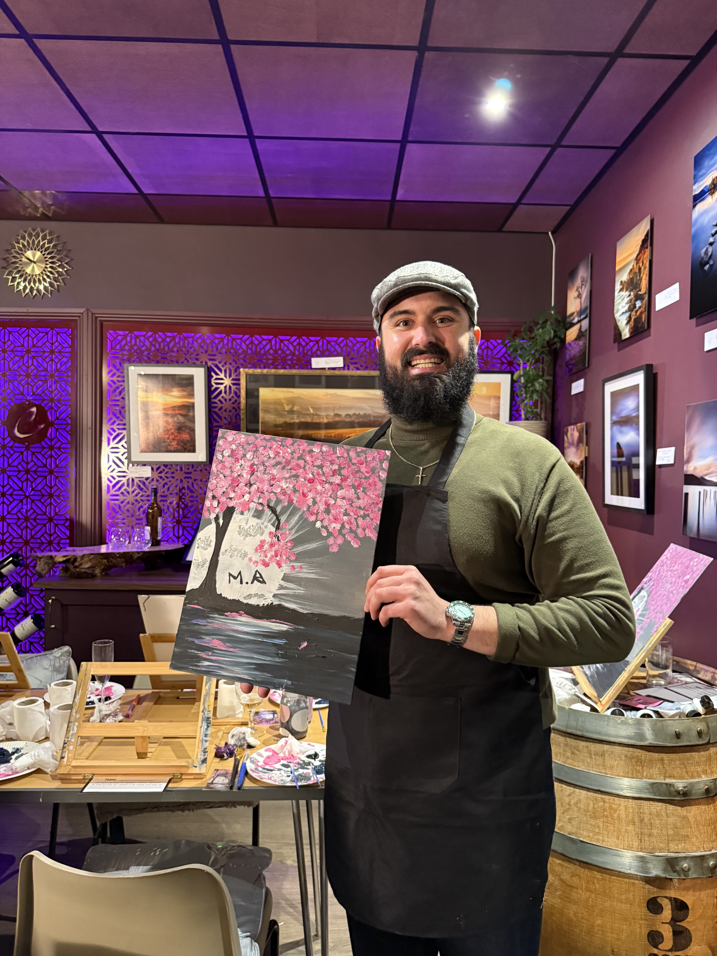 A Canvas & Cava guest proudly holding their finished painting during a guided paint and sip night in Brighouse, near Halifax and Huddersfield. Hosted at Czerwik Fine Wines & Cheeses, guests follow step-by-step instruction while enjoying drinks and a 