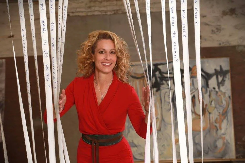 Jean Kiernan Detjen standing among poetry installation in Take Me to The River art exhibit she curated in Wisconsin.