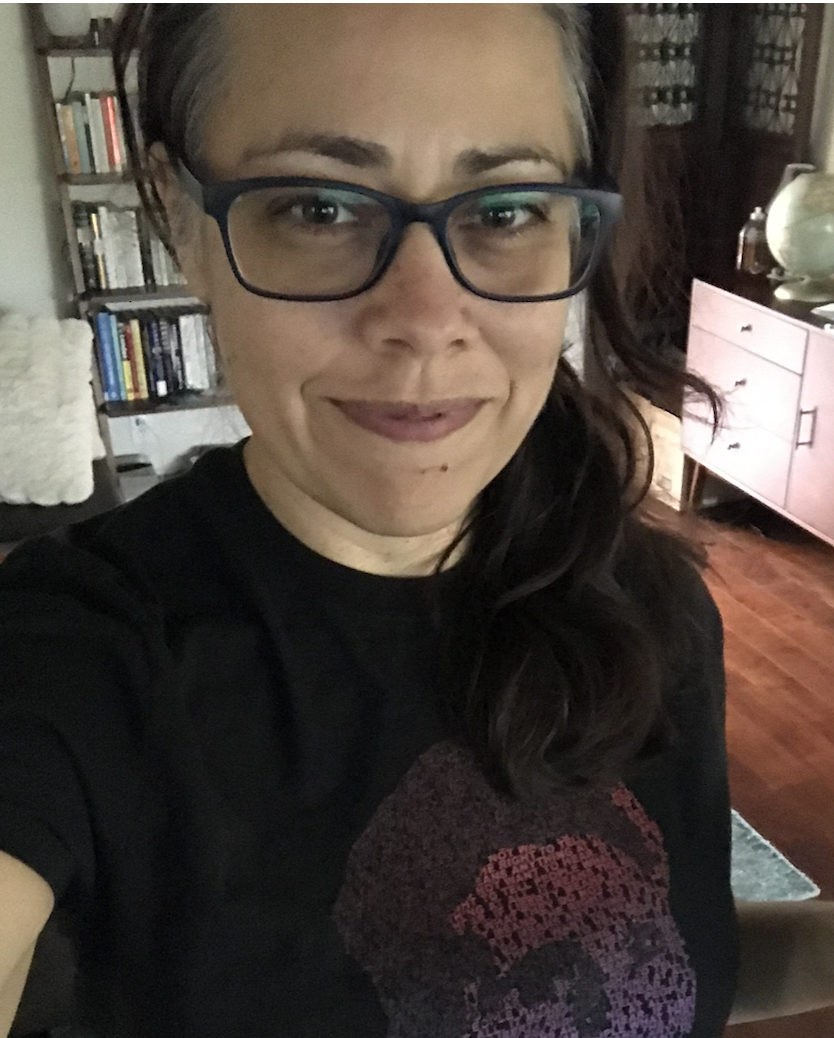 Jocelyn Kerr selfie in a living room with bookshelves, a dresser, and a globe in the background.