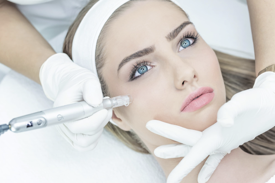 Woman receiving a cosmetic facial treatment with a pen-like device, lying down with a white headband, in a clinical setting.