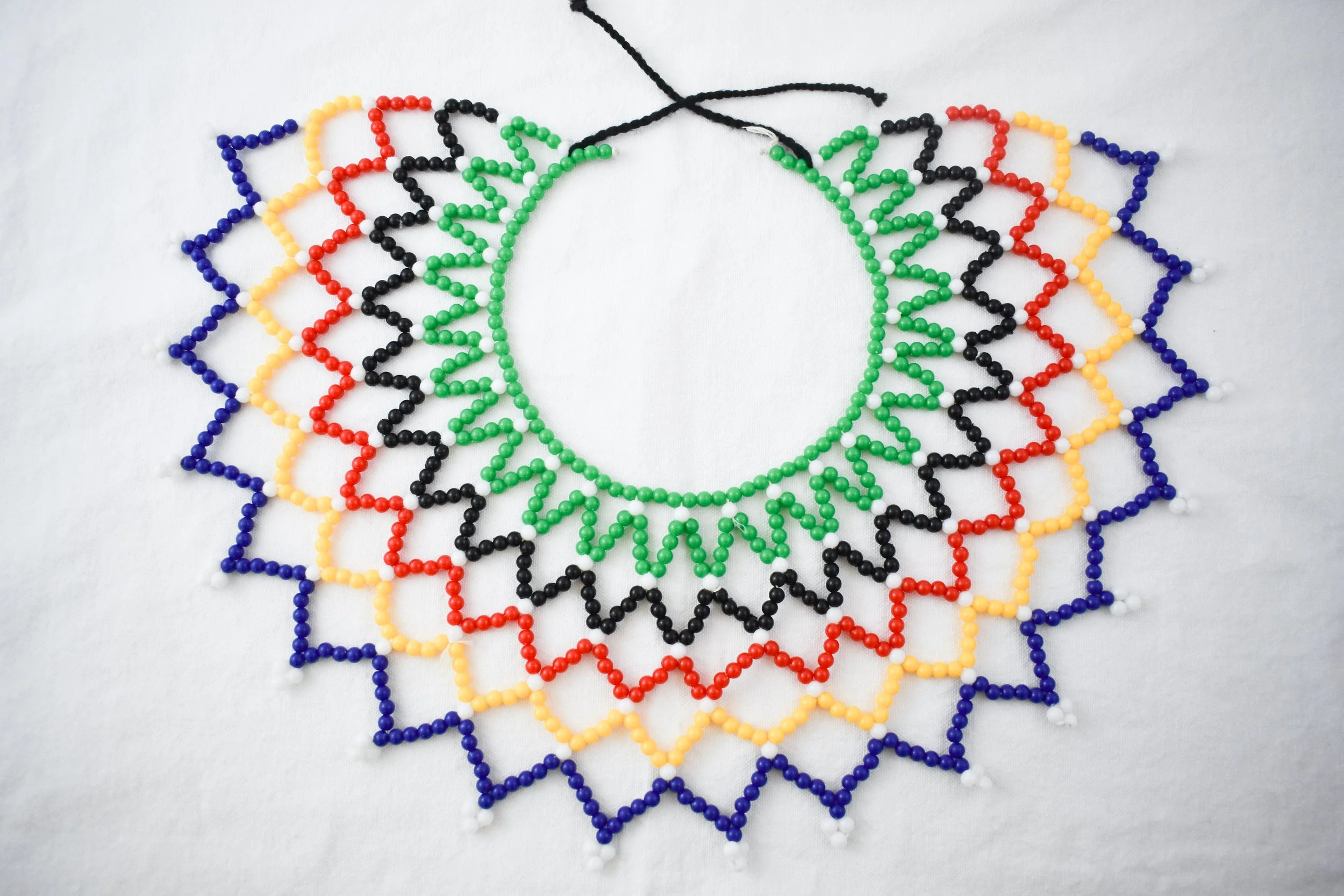 A traditional Zimbabwean beaded necklace. Beadwork is traditionally done by women as a way to pass the time and spend time with family when not working in the fields. Traditional beads are sourced from tree seeds, stones, and fabric.