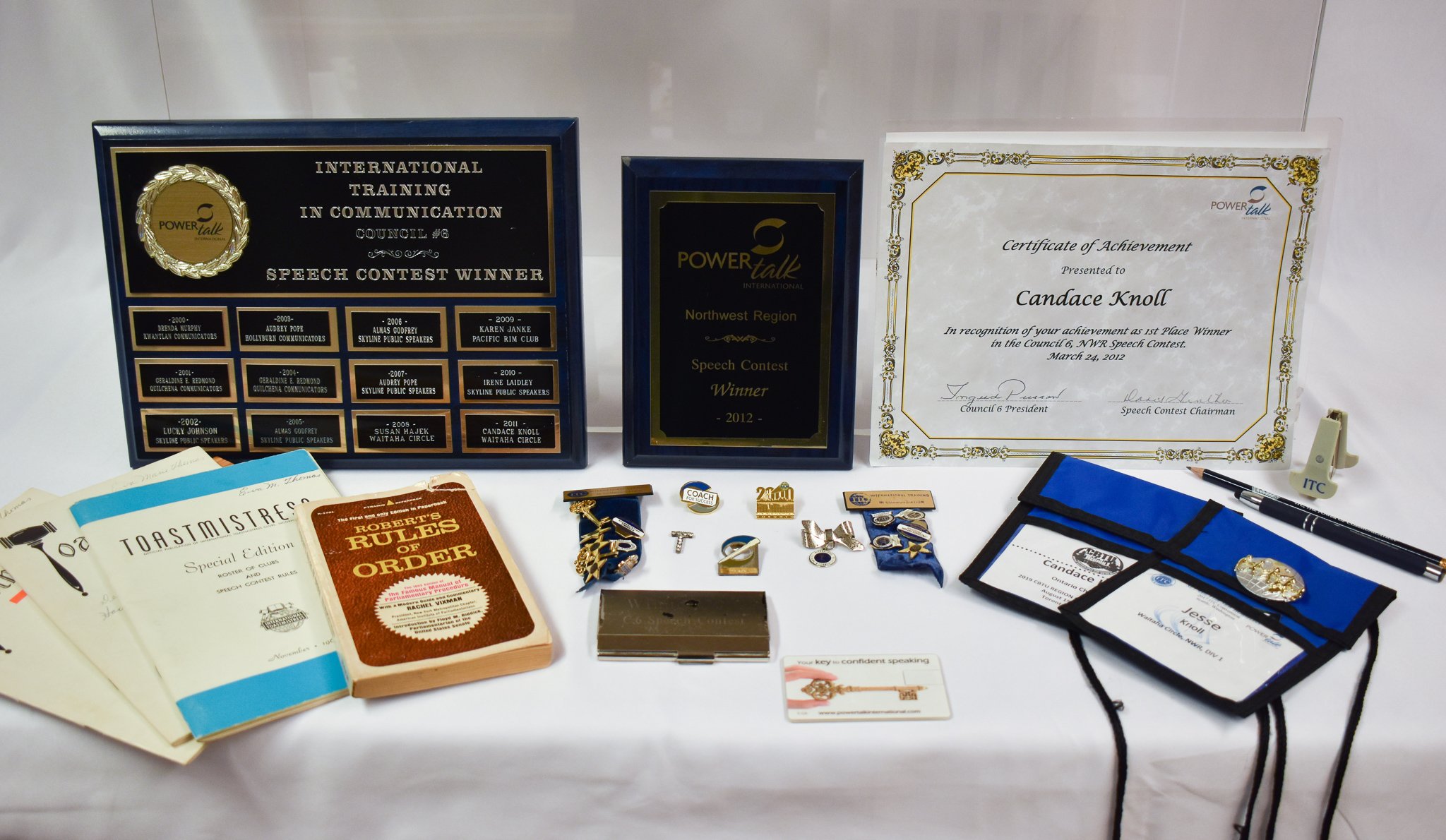 Some more Toast Mistress souvenirs and awards. Back row (L to R): plaques from various PowerTalk competitions where Candace won speech contests. Front row (L to R): Various editions of rule books for Toastmistresses; pins from various Toastmistress e