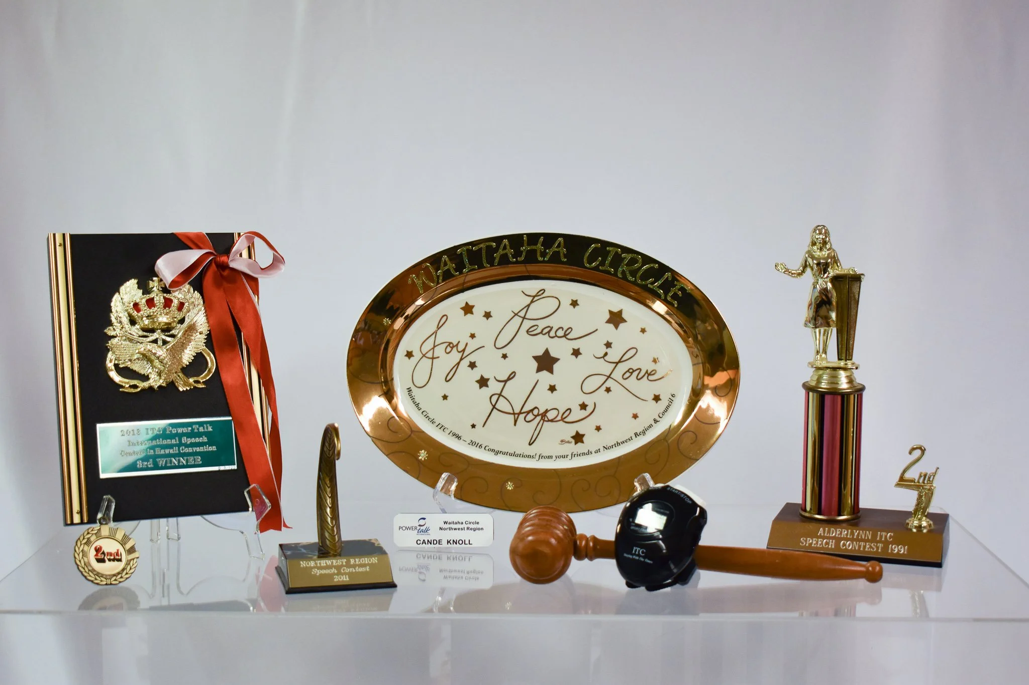 This photograph shows some items from Candace’s involvement with Toast Mistresses, (now ITC). (L to R): 3rd place award from the 2018 ITO PowerTalk Convention (competition for public speaking); 2nd place award from 2011 Northwest Region Speech Contes