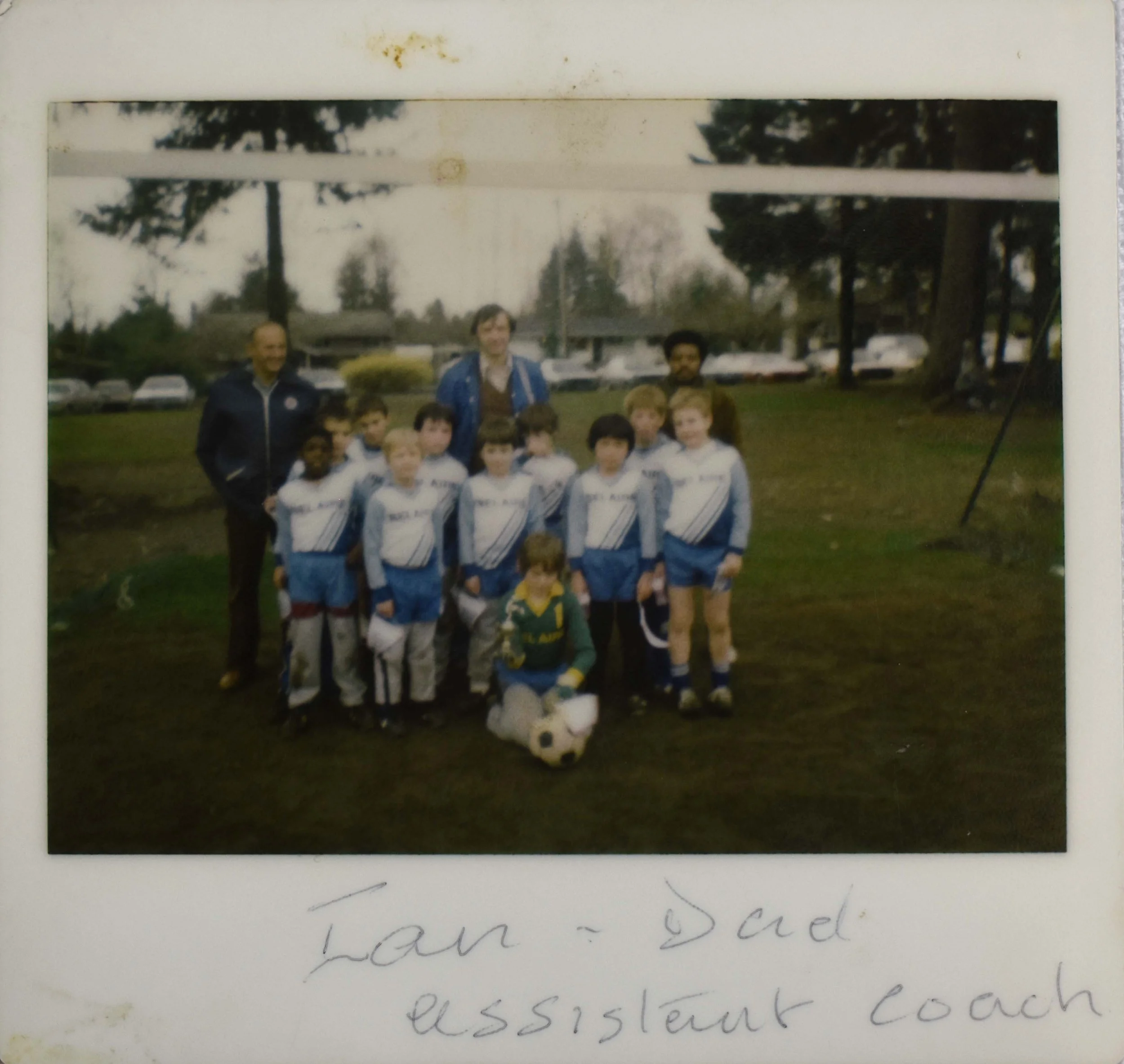 Photo of Ian playing little league soccer with his dad, George, as assistant coach.