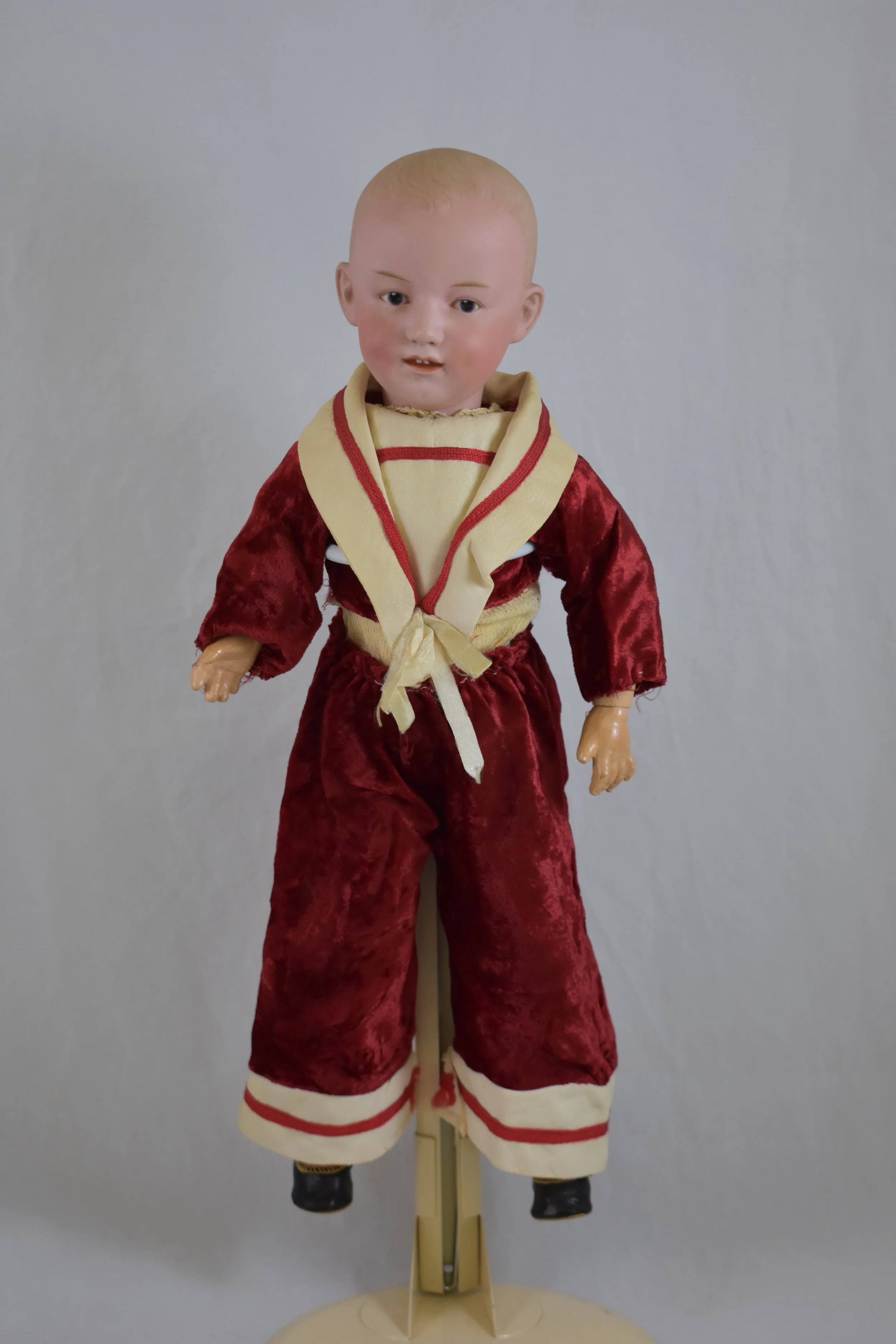 A jaunty Gebruder Heubach boy doll, in red velvet, without his hat....