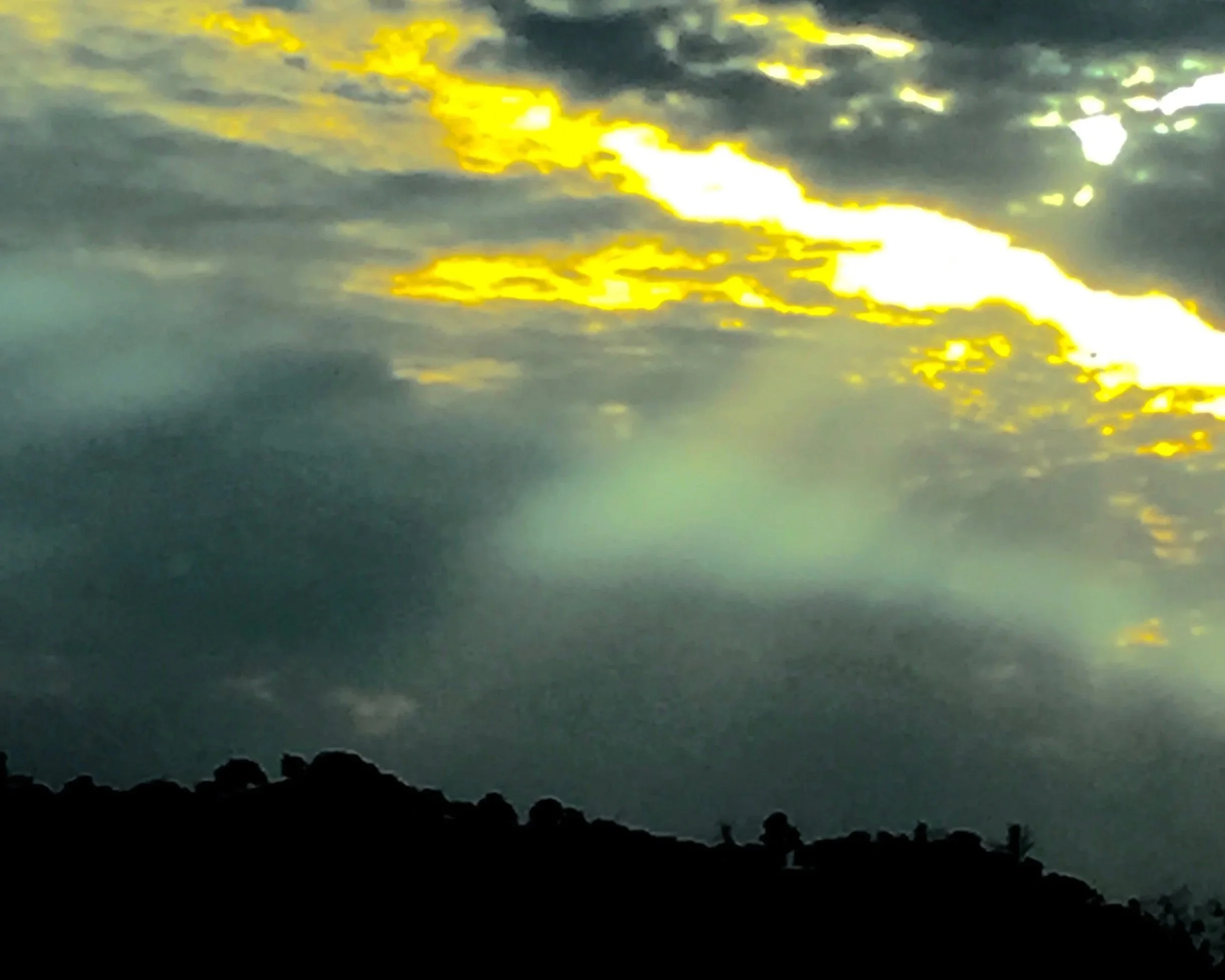 Sunlight breaking through dark clouds over a landscape