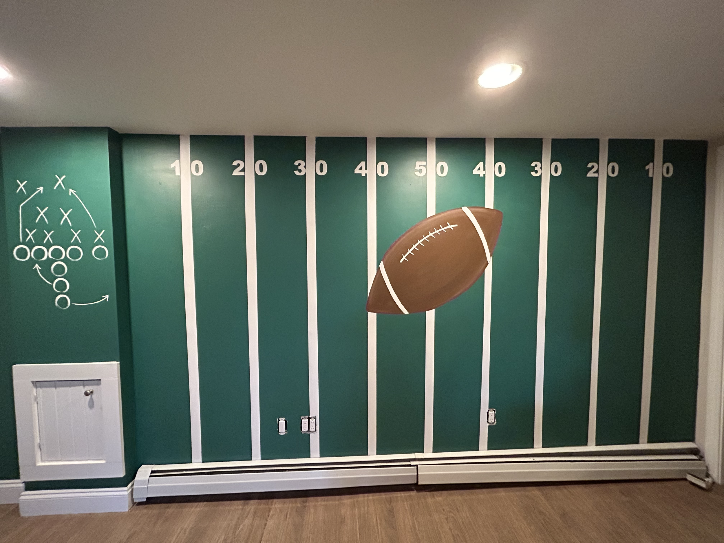 Football-themed exercise wall mural with yard markers from 10 to 50, a large football graphic in the center, and a strategic play diagram on the left.