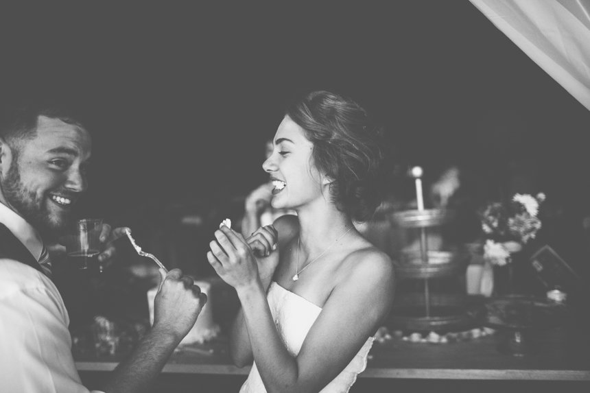 A joyful couple at a celebration, sharing a moment with ice cream and a cake in the background.