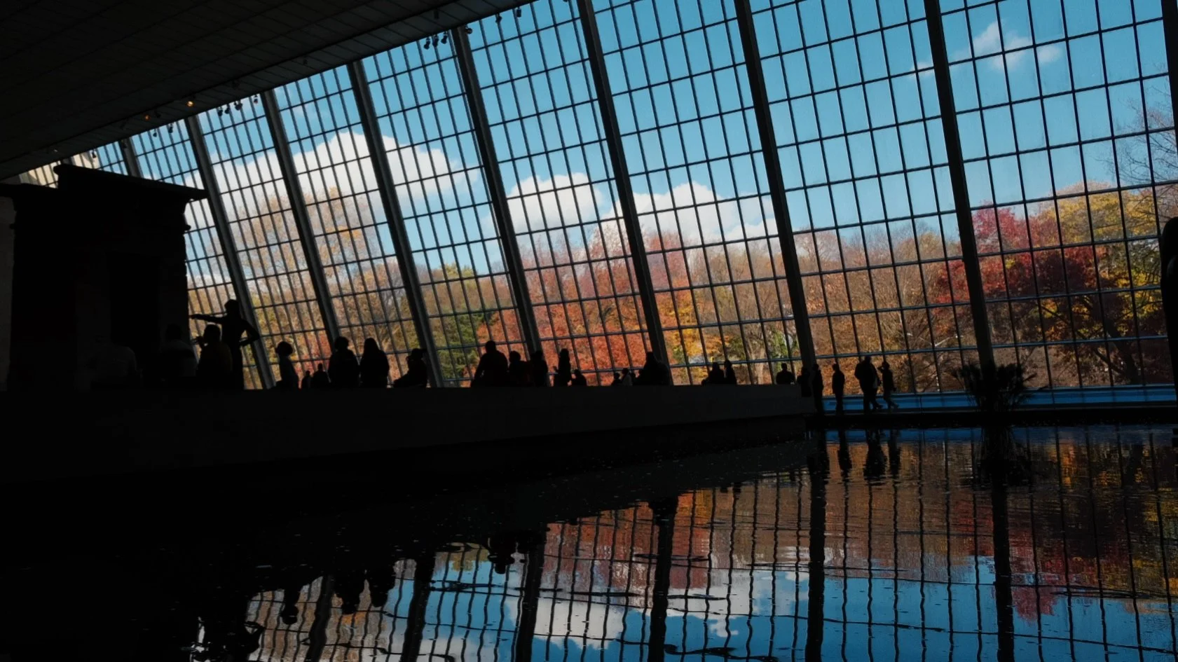 NEW YORK, NY — Visitors gather in the
Temple of Dendur gallery at The Metropolitan Museum of  Art in November 2024, silhouetted
against the floor-toceiling windows overlooking Central Park’s autumn colors.