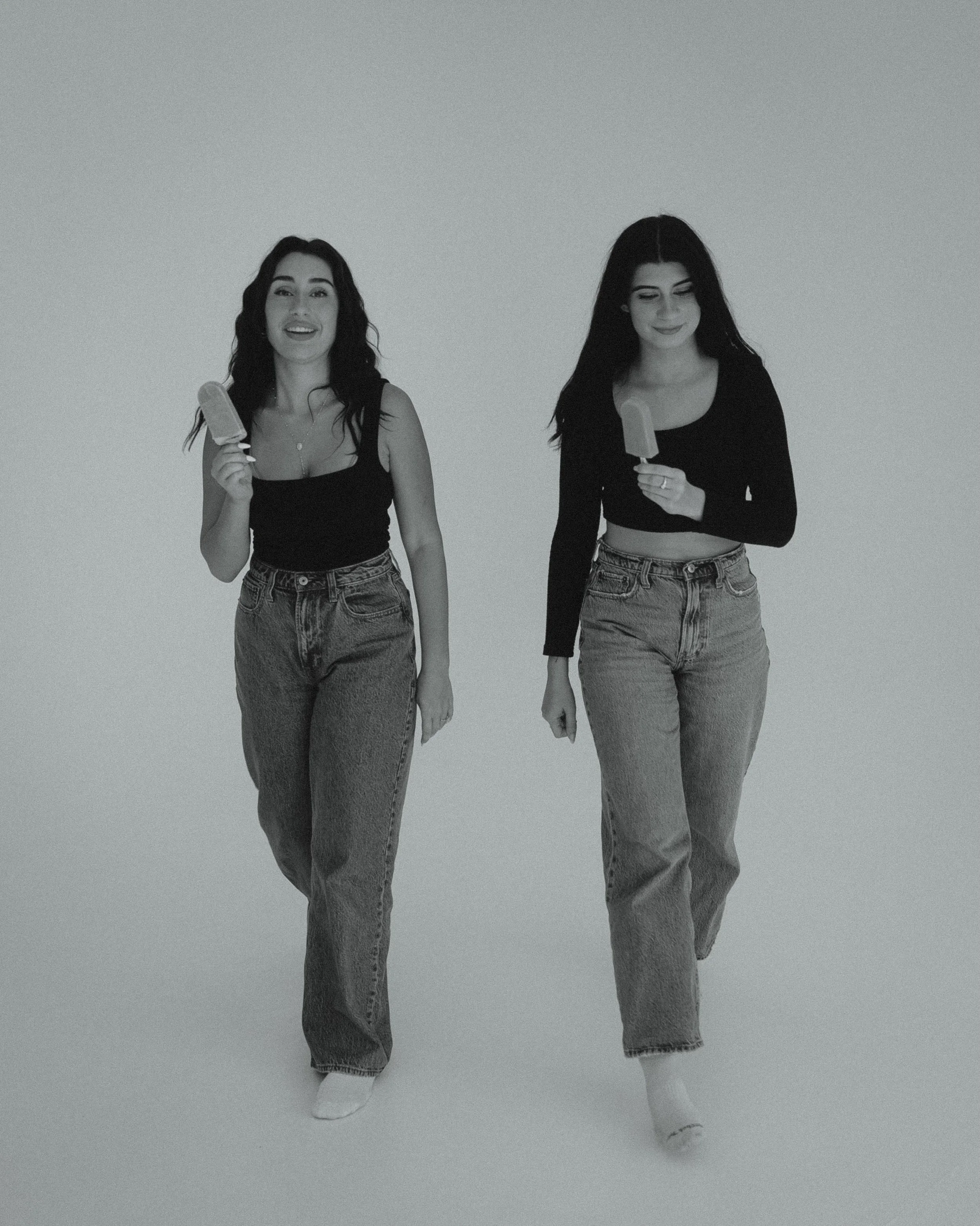 Two women walking together, each holding an ice cream bar.