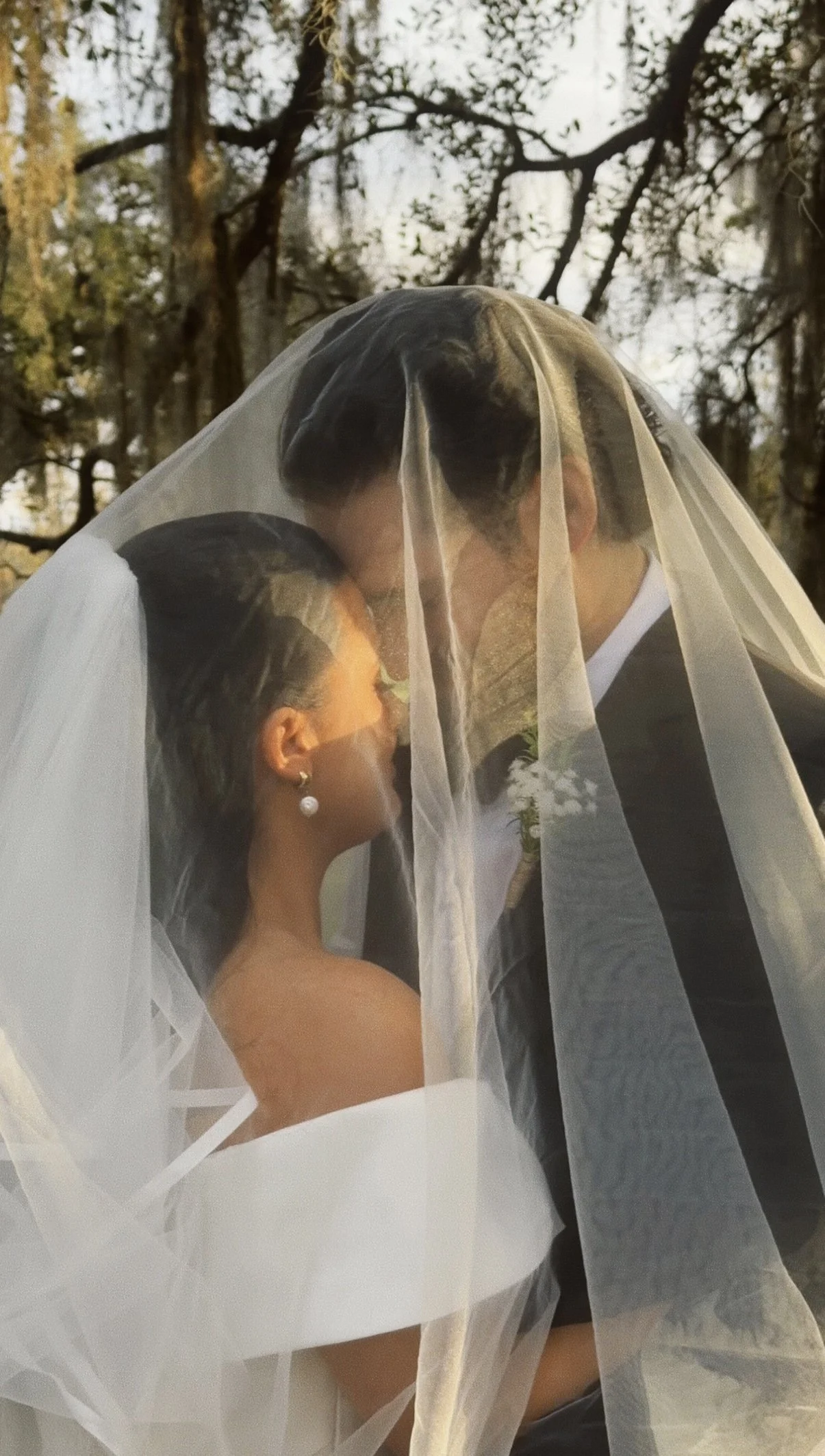 A bride and groom sharing a close, intimate moment under a veil outdoors, with trees in the background. Wedding Content Creator, Louisiana Wedding Content Creator, New Orleans Wedding Content Creator, Baton Rouge wedding Content Creator