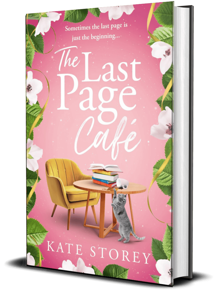 A pink book cover titled "The Last Page Cafe" by Kate Storey. The cover features a cozy scene with an armchair, a round wooden table holding a stack of books, an open book, and a cat reaching up to a cup on the table. The border has green leaves and white flowers.