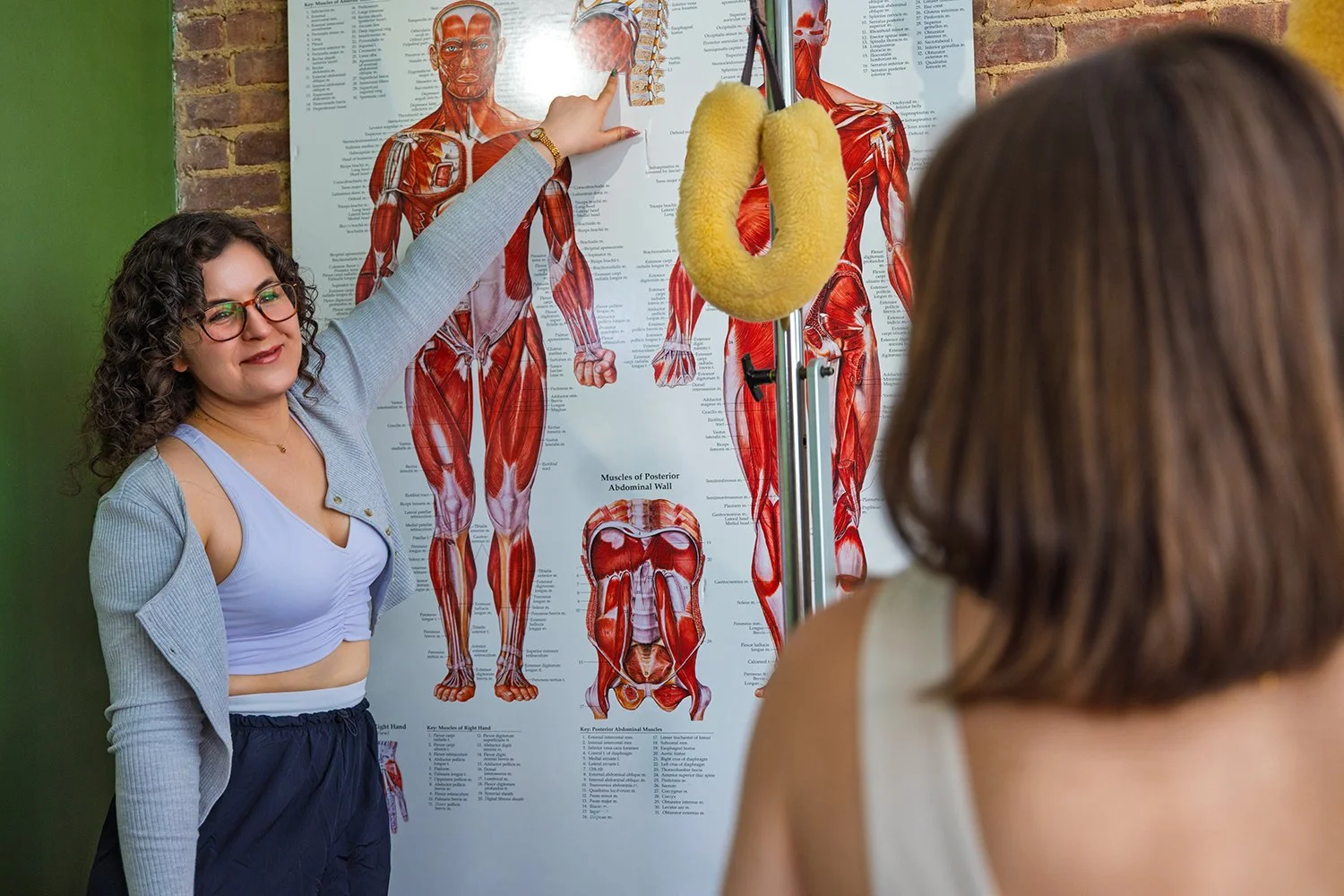 A Pilates instructor teaches anatomy and biomechanics to her students in a studio space