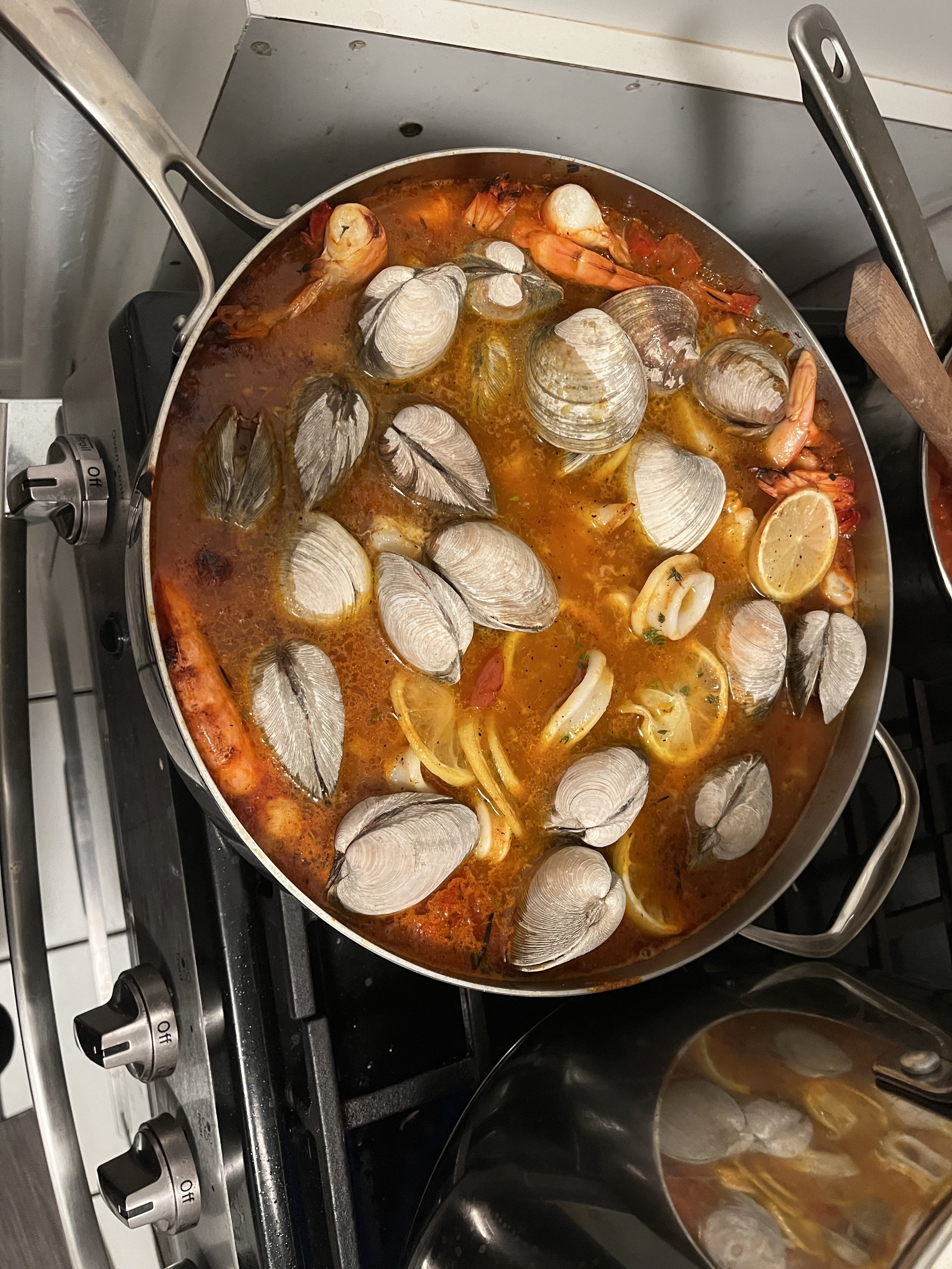 Seafood stew with clams, shrimp, and squid in a spicy broth with lemon slices.