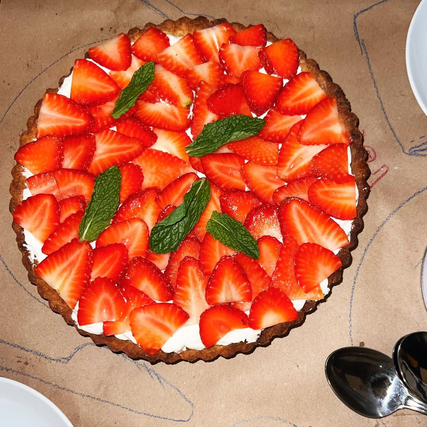 Strawberry tart with fresh sliced strawberries and mint leaves on top.
