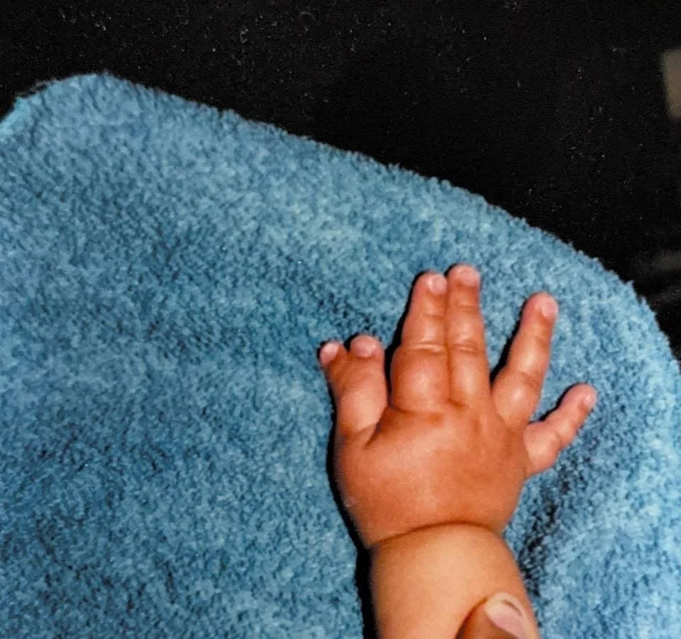 Close-up of Michael's hand as a baby resting on a soft, fuzzy blue blanket.