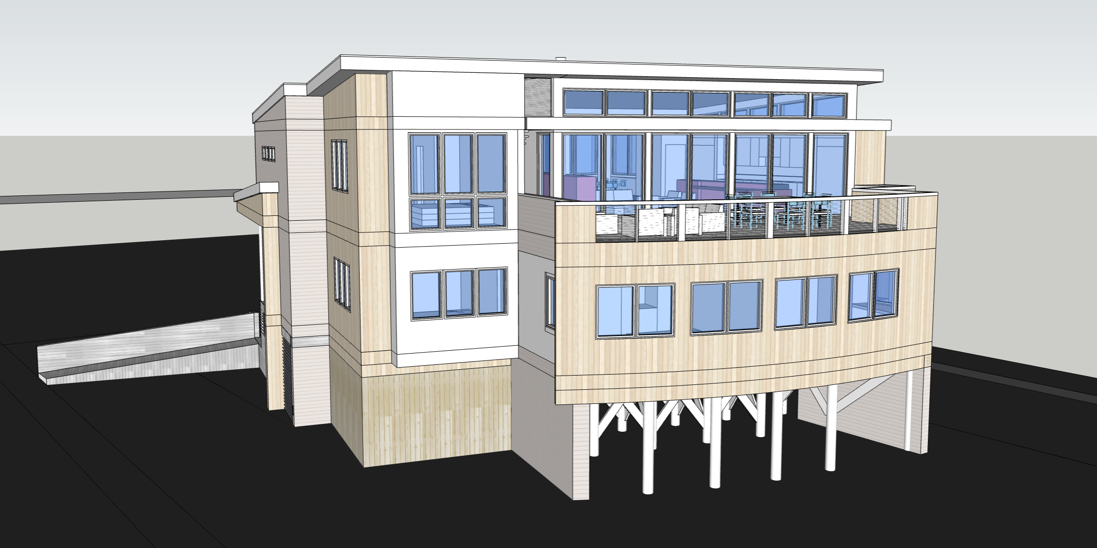 Modern black multi-story house with large windows, surrounded by trees with autumn leaves, under a partly cloudy sky.