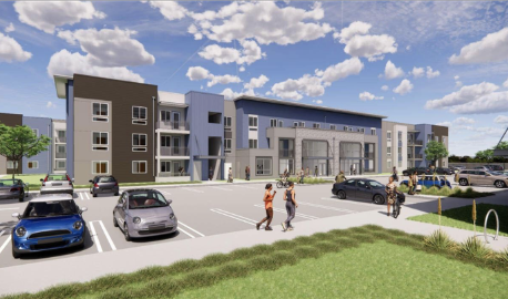 Modern apartment complex with parked cars and people walking in the parking lot.