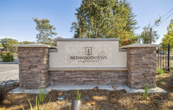 Entrance sign for Redwood Views Apartments with brick columns and a light-colored center panel.