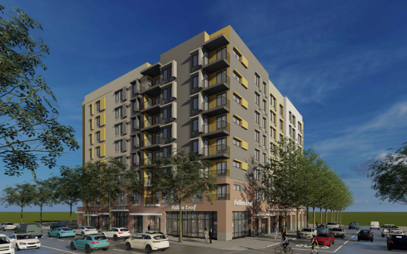 New multi-story apartment building with retail shops on the ground floor, surrounded by parked cars and green trees under a blue sky.