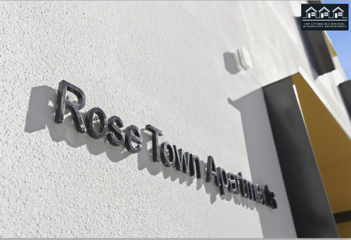 Close-up of the exterior wall of Rose Town Apartments with a sign showing the name and shadow shadows cast by the letters