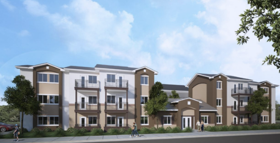 A multi-story residential apartment building with balconies, trees, and a sidewalk in front under a partly cloudy sky.