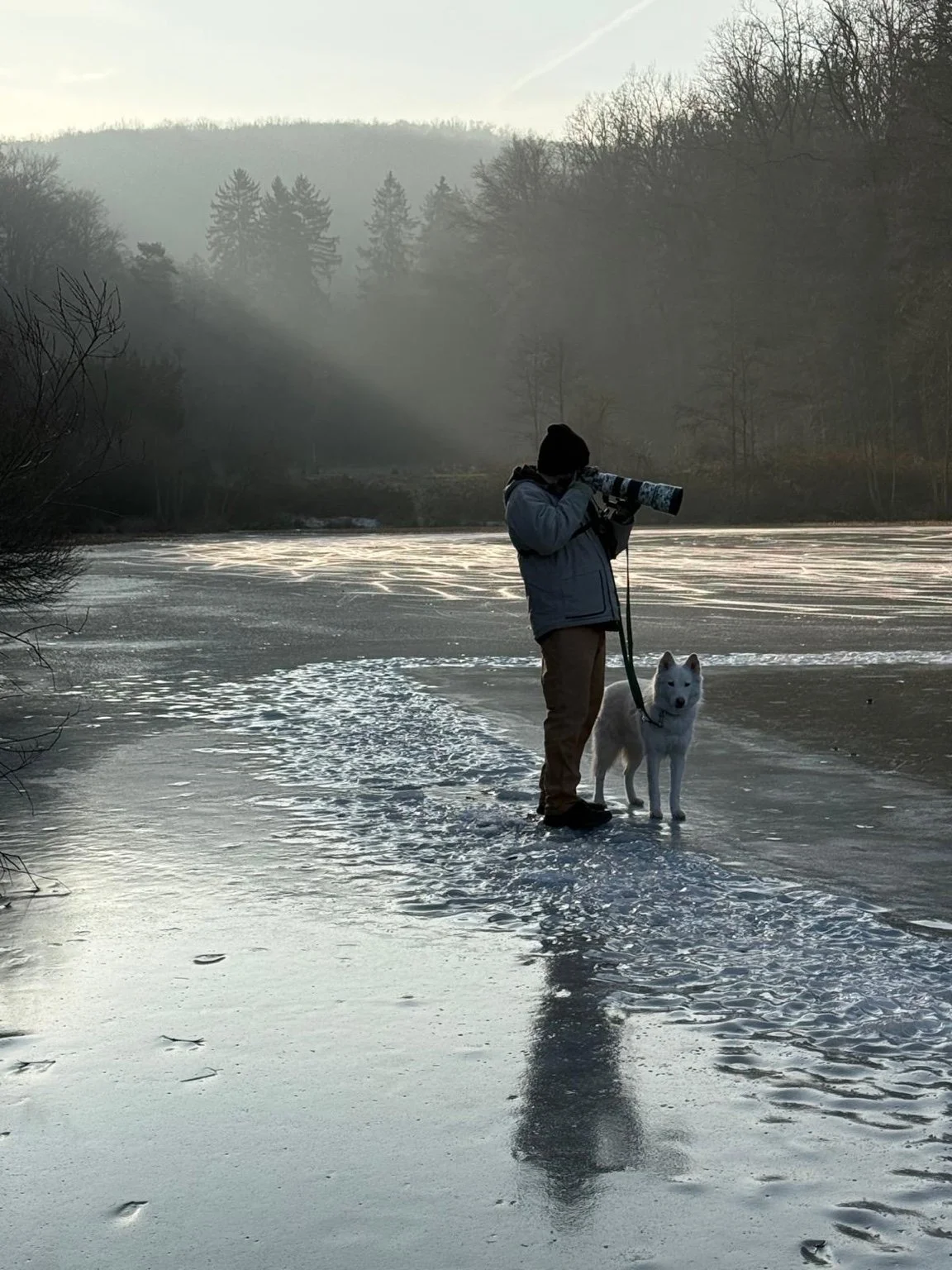 Joseph Hubbard wildlife photographer working on a frozen lake in Germany with telephoto lens during winter sunrise