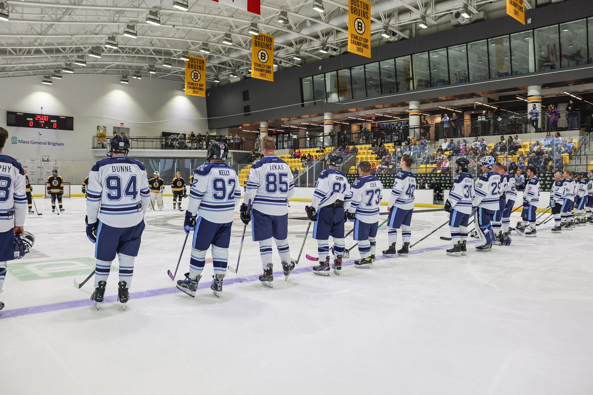 The JetBlue Hockey team lined up facing the Boston Bruins Alumni on the blue line at the Warrior Ice Arena during the national anthem.