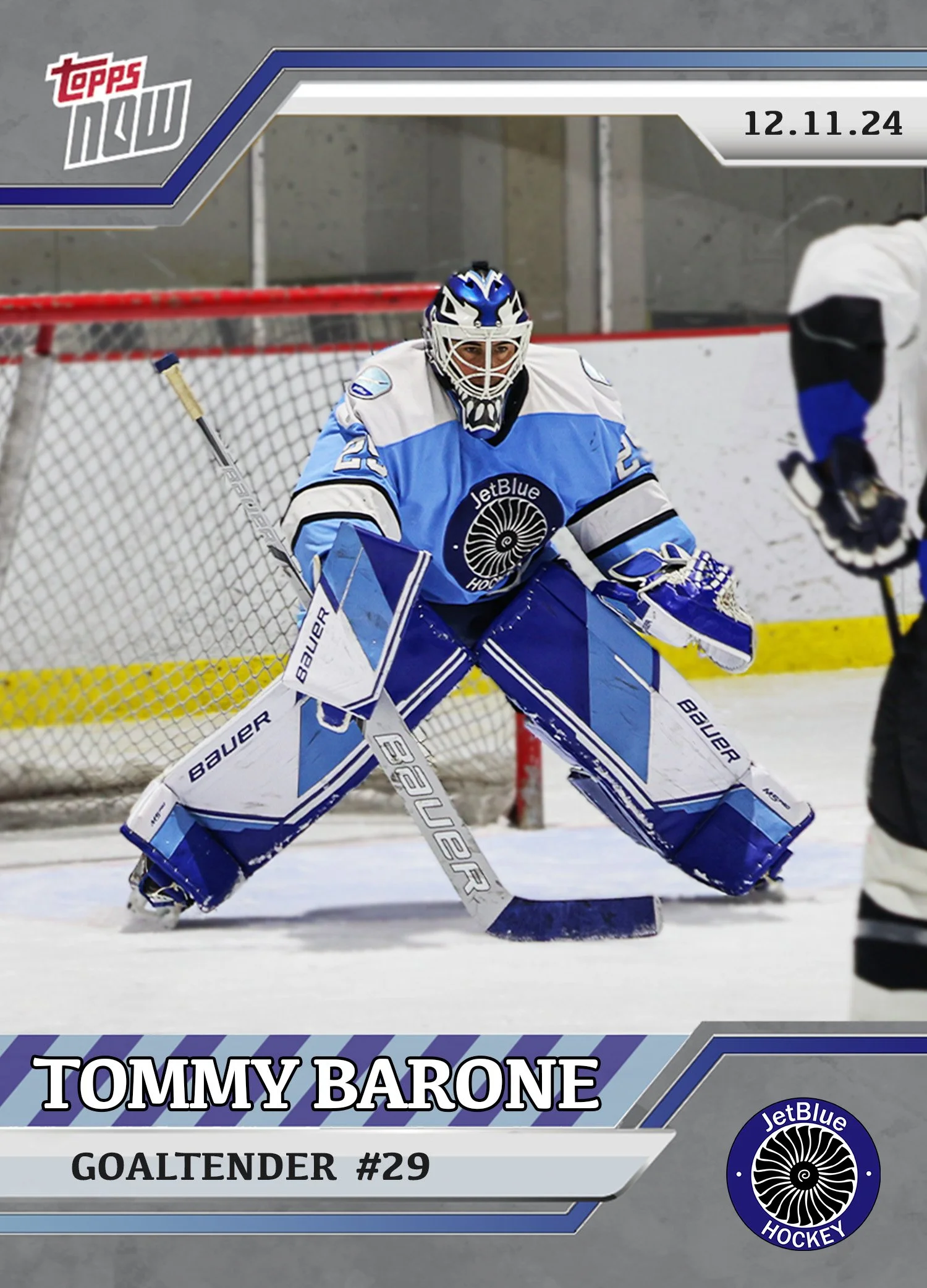 An ice hockey goalie in a blue and white uniform with the JetBlue logo, wearing a helmet and pads, playing in an indoor rink.