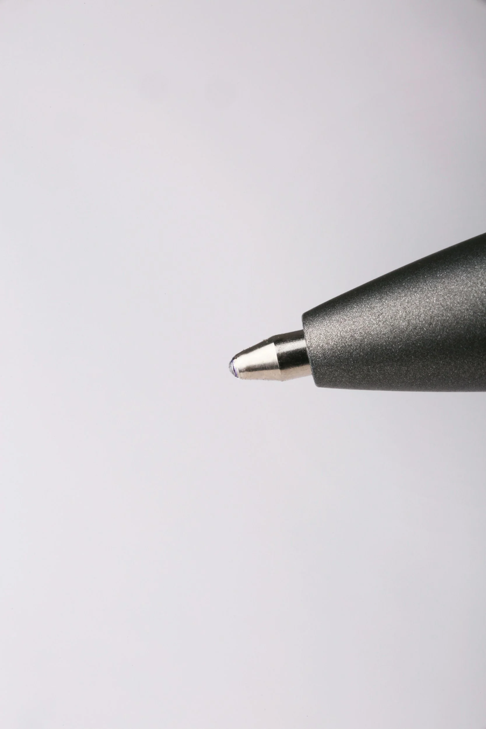 Close-up of a black marker pen tip on a blank white surface.