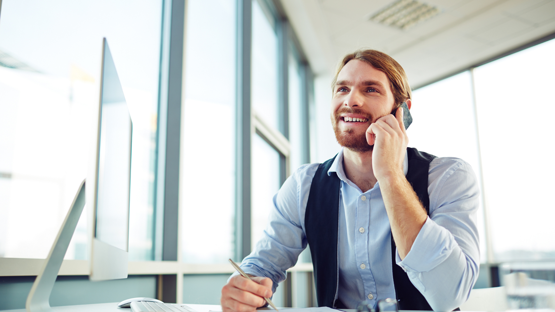 Consulente immobiliare durante una consulenza telefonica in ufficio, specializzato in valutazioni e analisi immobiliari.