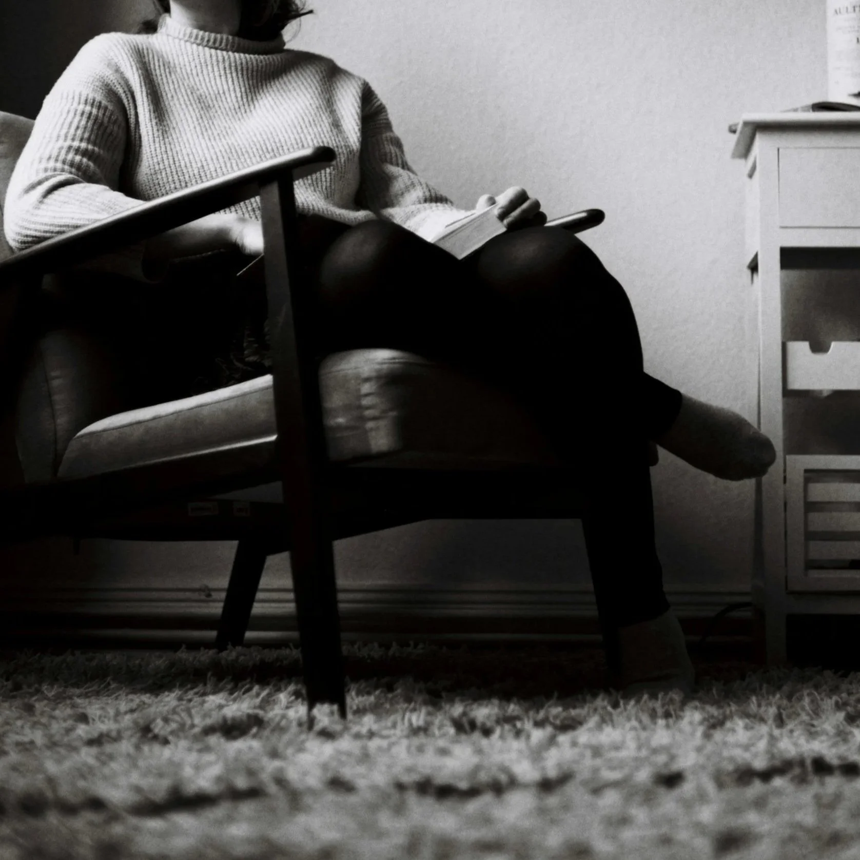 Black-and-white photograph of a seated person writing in a notebook.