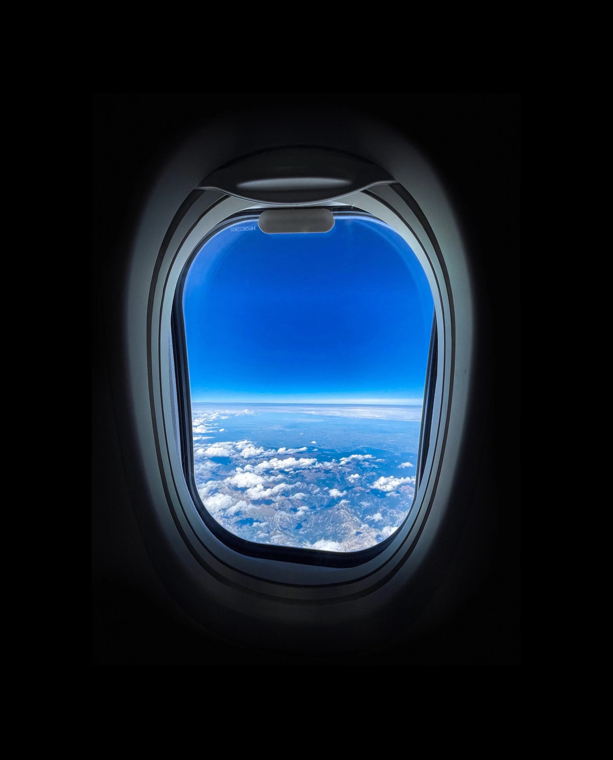 Vue depuis une fenêtre d'avion montrant des nuages et le ciel bleu.