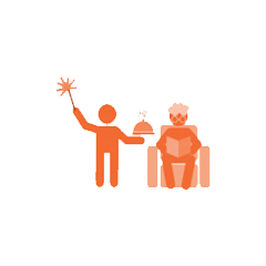 A person standing and holding a tray with a cake, and another person sitting in a chair reading a book.