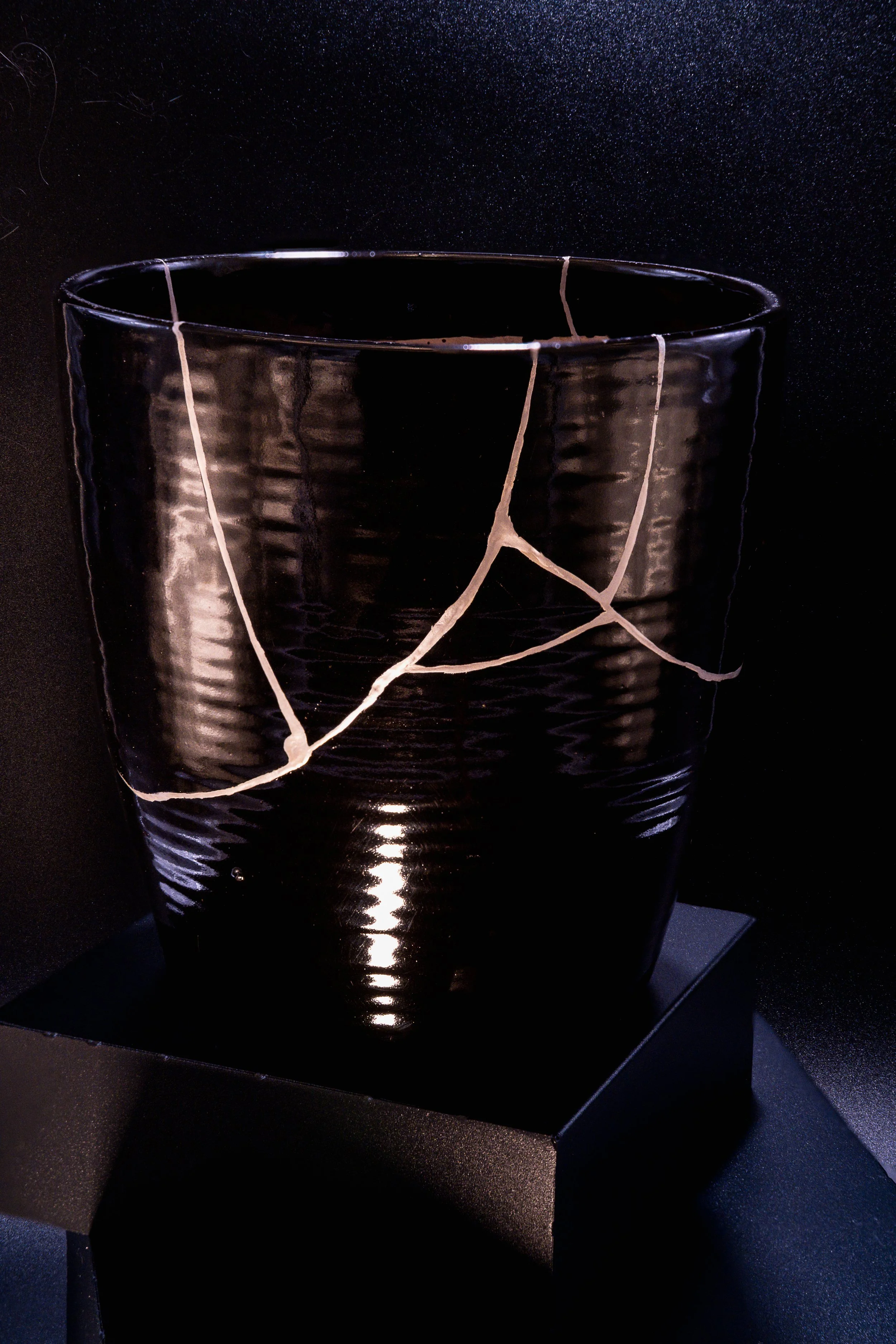 A black glass with white cracks resting on a black surface.