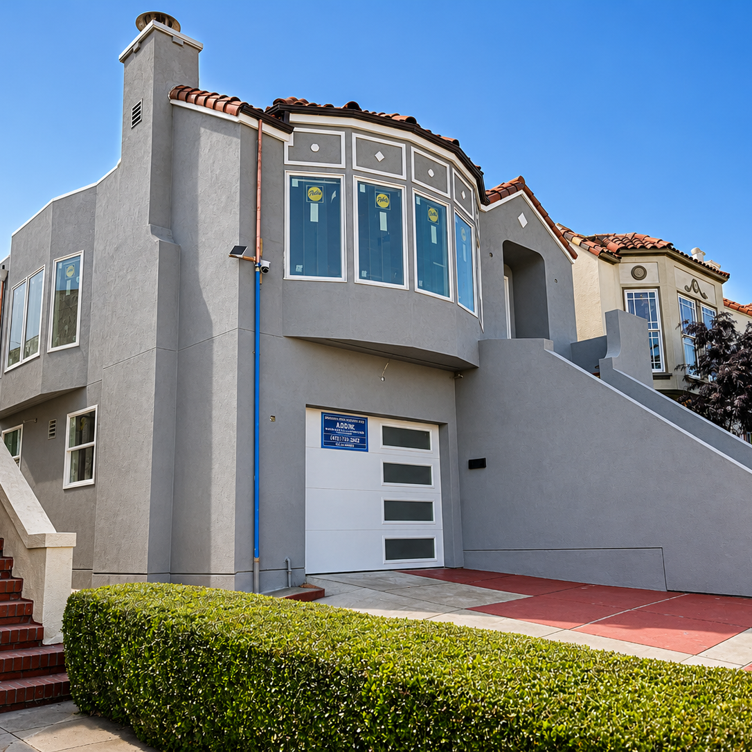 White modern two-story house with black door, glass garage door, staircase on right side, and small landscaped yard with rocks.